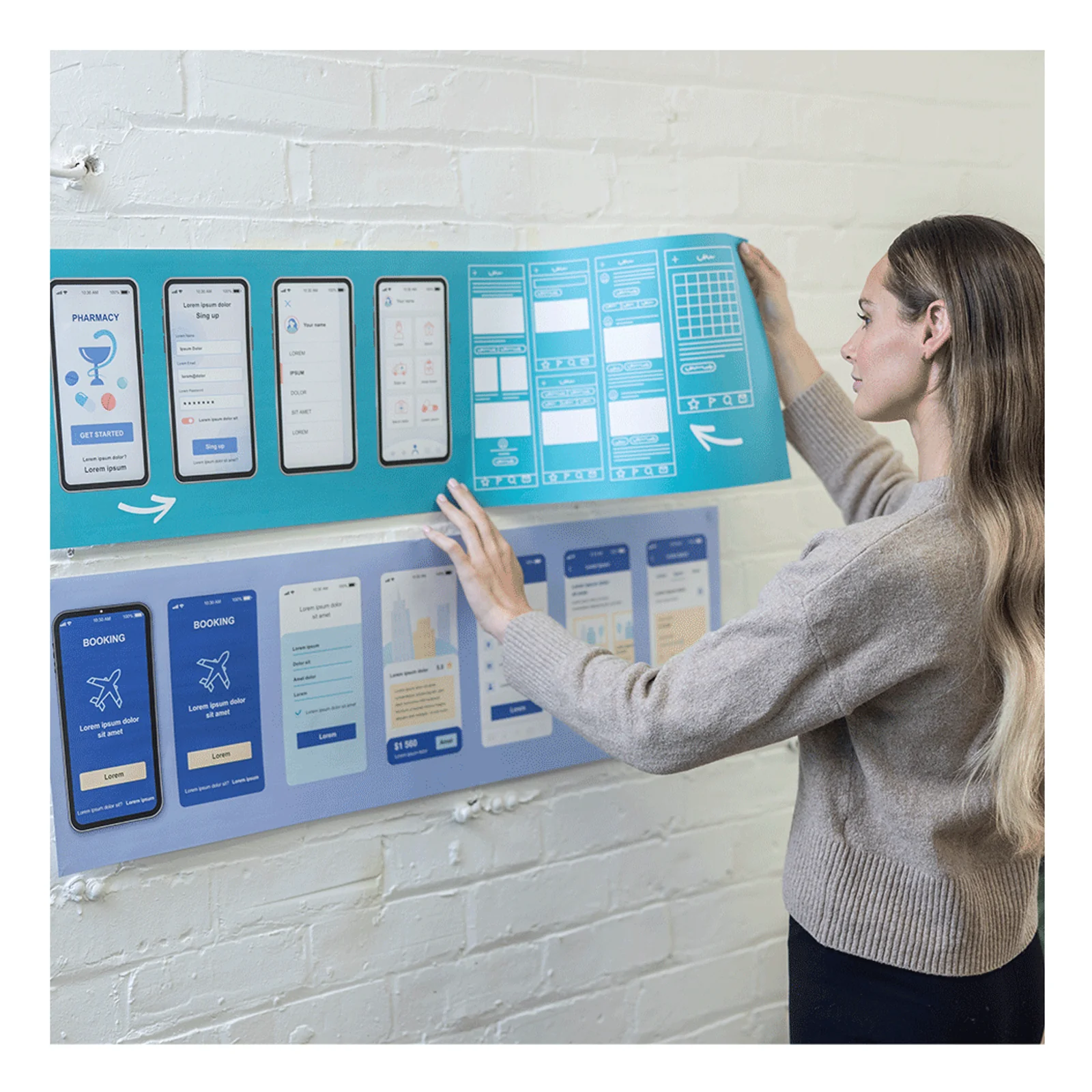Femme accrochant au mur de brique blanche des planches A3 d'interface mobile imprimees en bleu turquoise