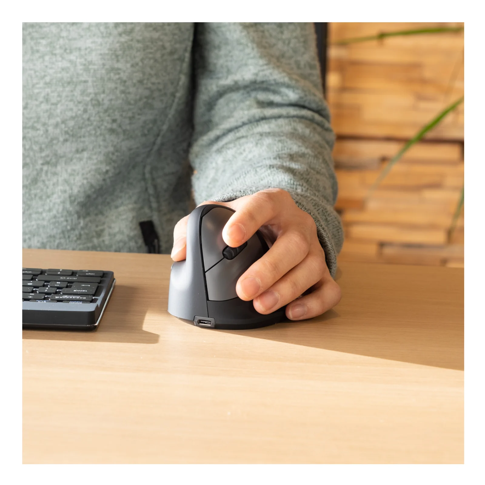 Main posée sur la souris R-Go HE Break à côté d'un clavier sur bureau en bois
