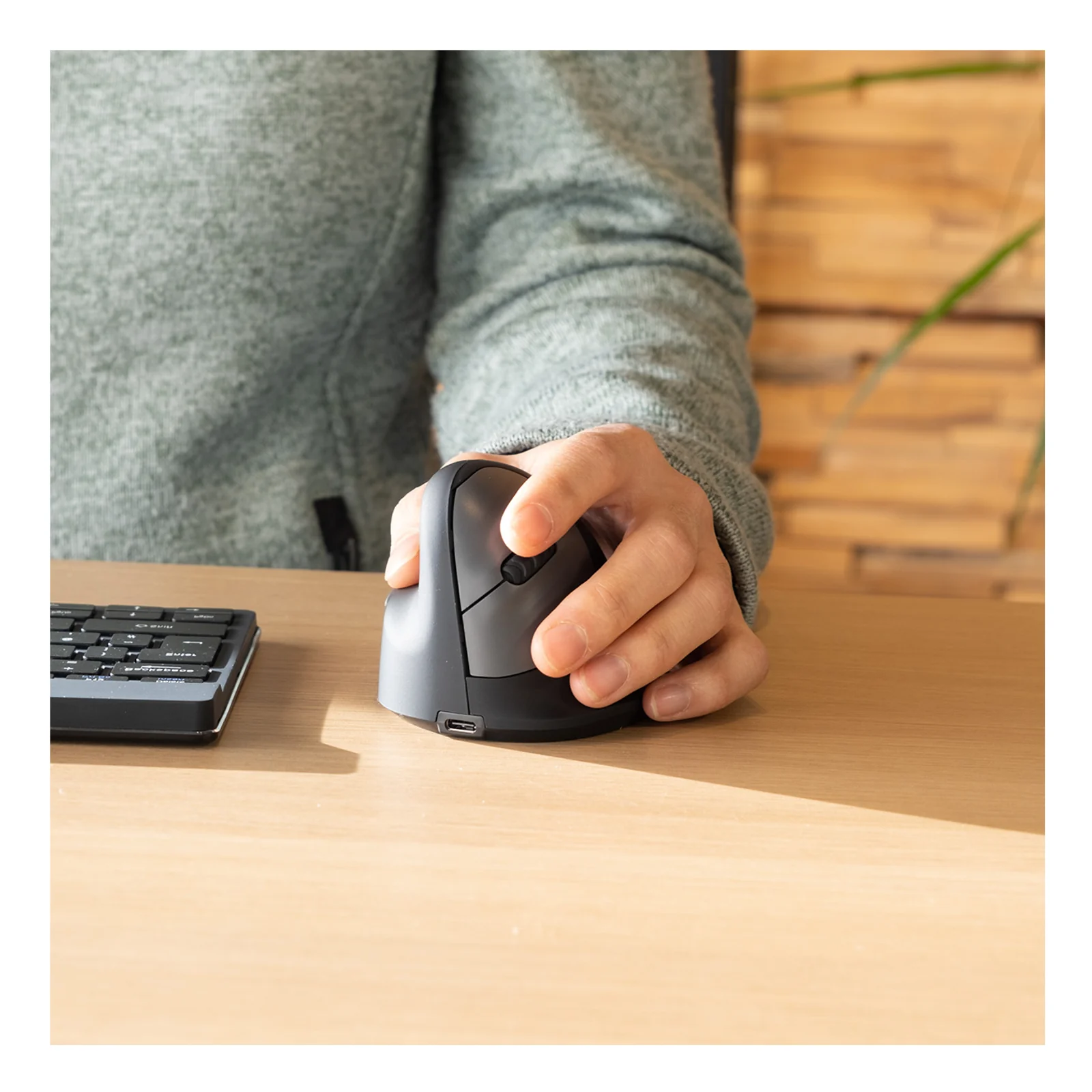 Main tenant la souris ergonomique R-Go HE Break sur bureau en bois, vue latérale