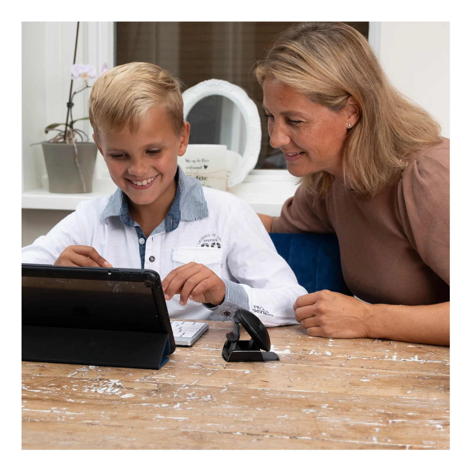 Mère et enfant consultant une tablette sur table, souris R-Go HE Twister visible en avant-plan