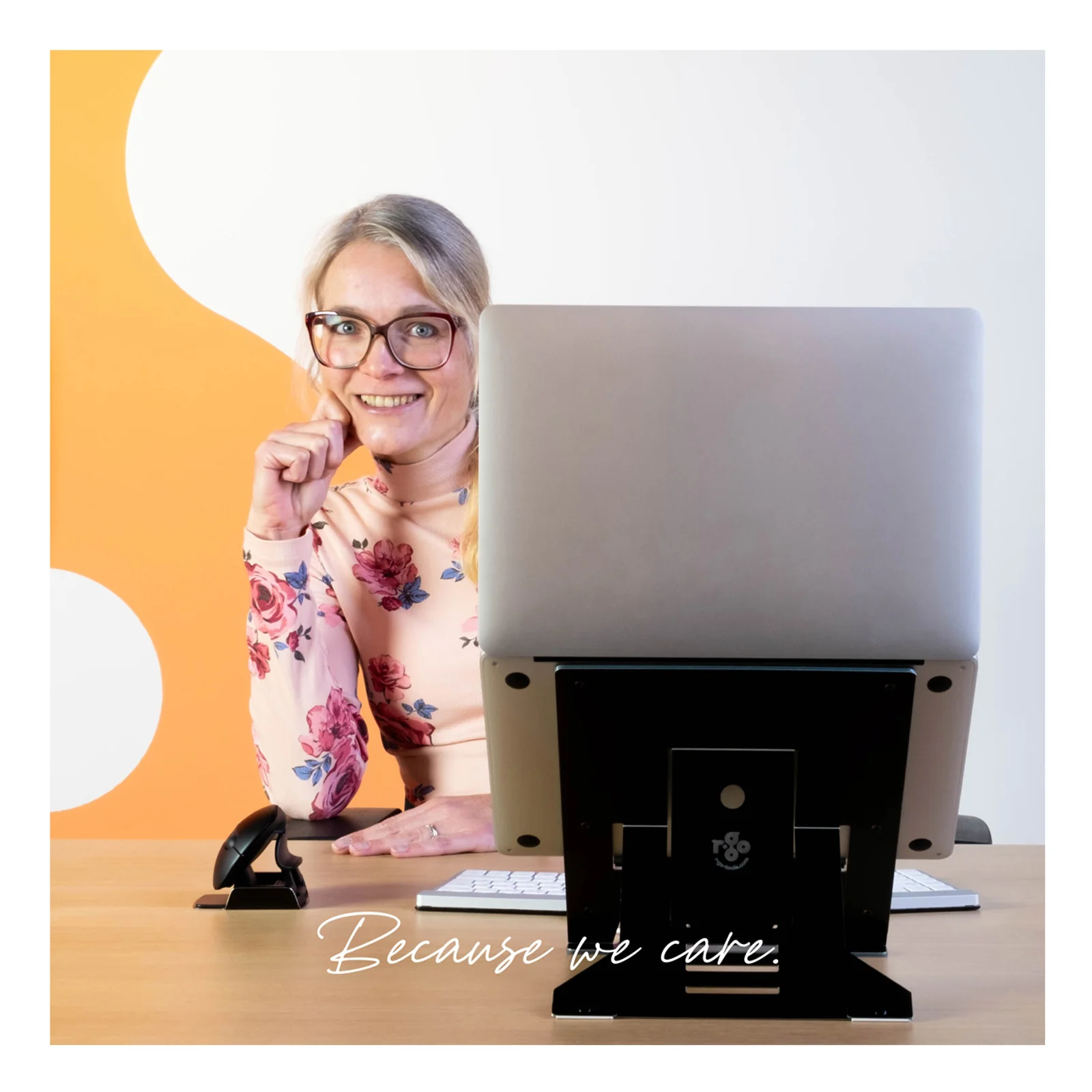 Femme souriante devant laptop sur support R-Go Riser Document noir, texte Because we care