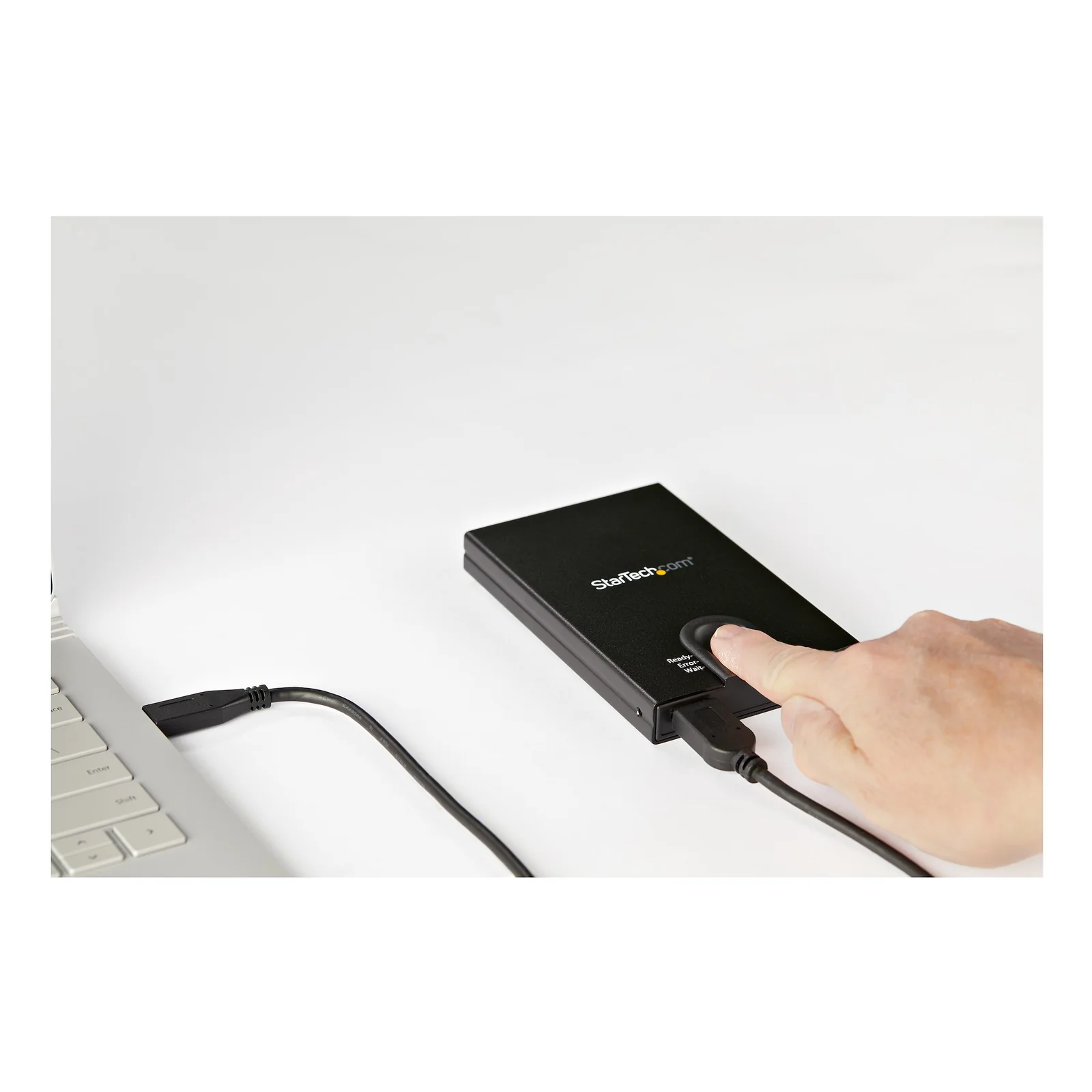 Main posant un doigt sur le lecteur d'empreinte du boîtier branché par câble USB à un ordinateur portable
