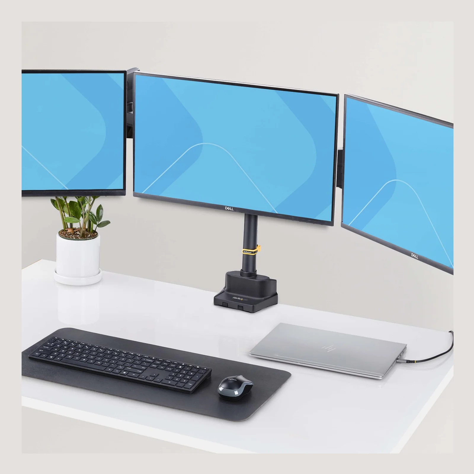 Vue lifestyle du support triple moniteur StarTech.com sur bureau compact avec 3 écrans Dell, ordinateur portable, clavier et souris.