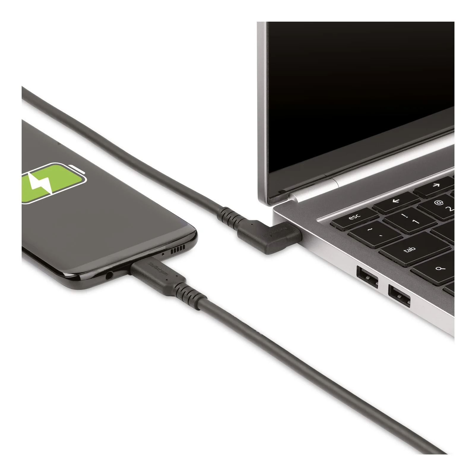 Câble USB-C noir branché entre un smartphone en charge et un ordinateur portable argenté, vue de côté