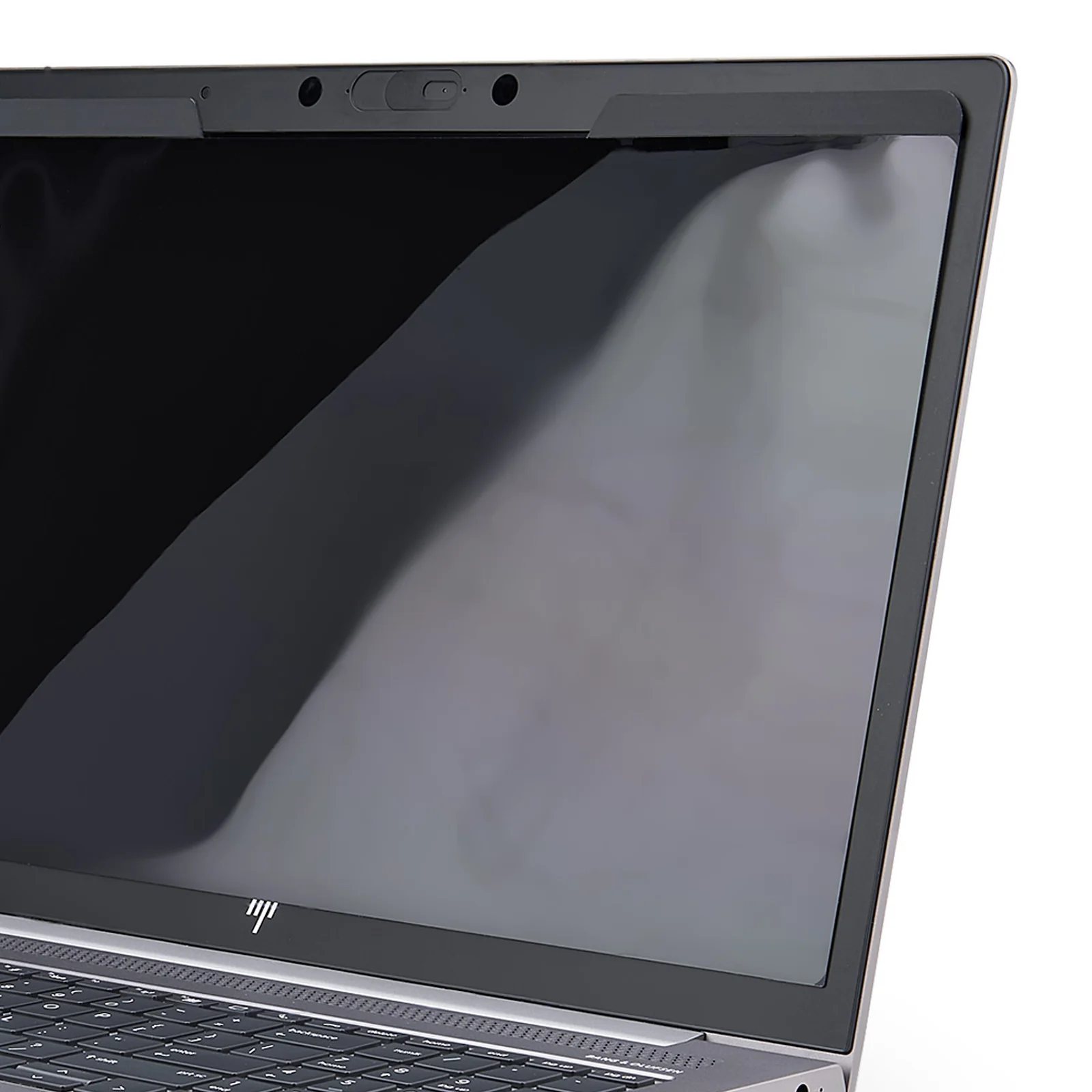 Gros plan sur le coin supérieur droit d'un écran de laptop recouvert par le filtre, surface gris foncé semi-réfléchissante