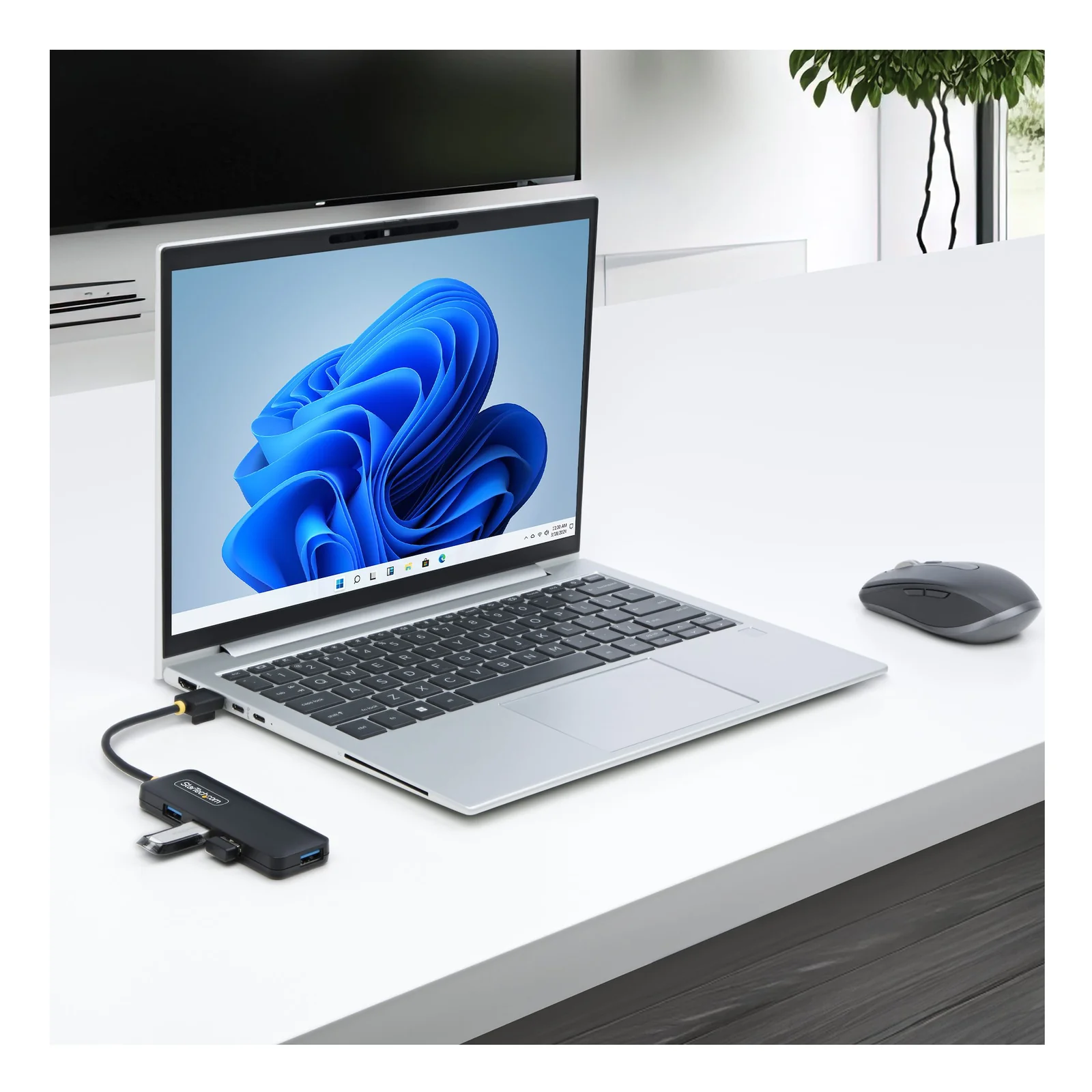 Hub USB-A 4 ports branché à un ordinateur portable argenté sur un bureau blanc, souris sans fil grise posée à droite