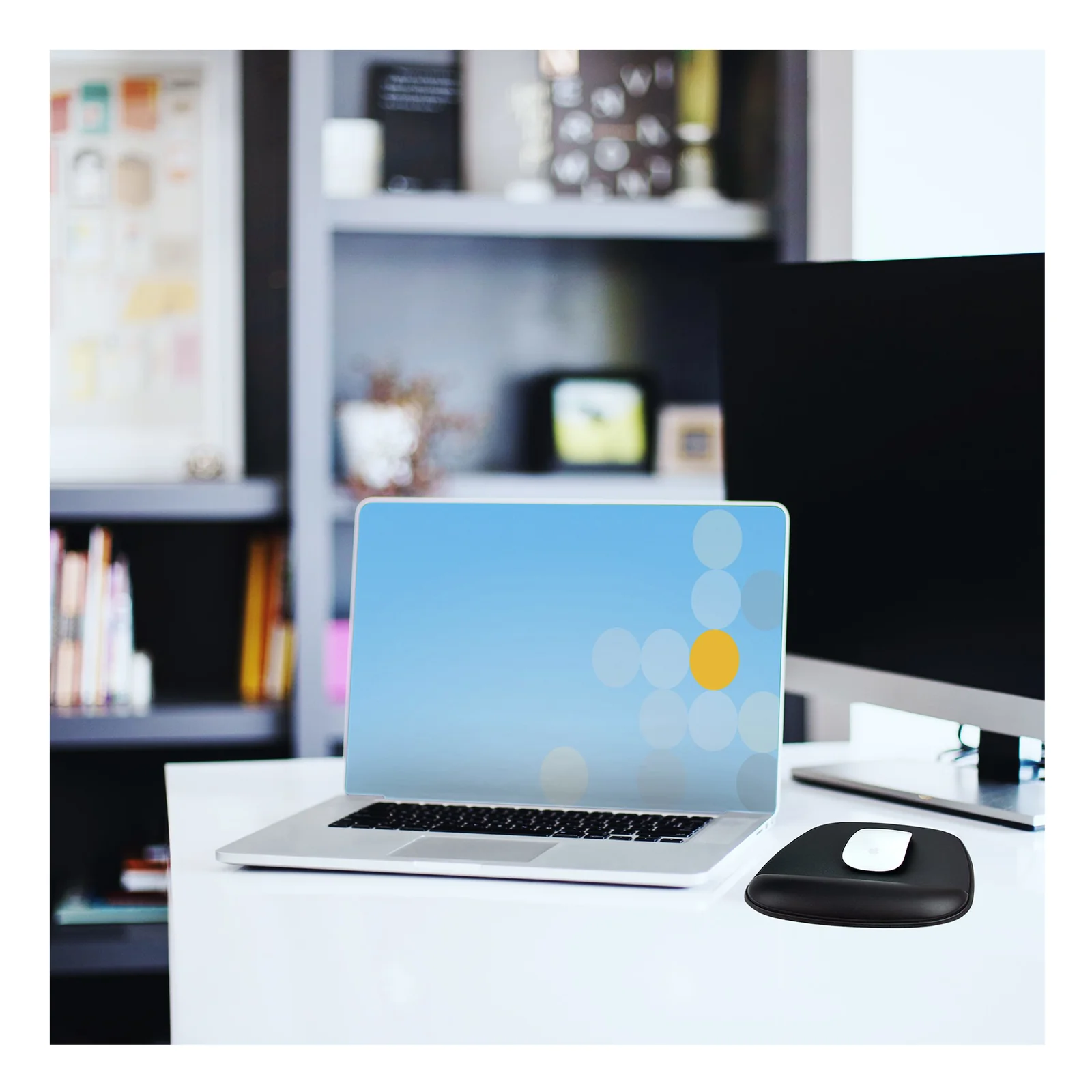Tapis de souris avec repose-poignets sur un bureau de bureau, souris blanche posée dessus, laptop ouvert à côté