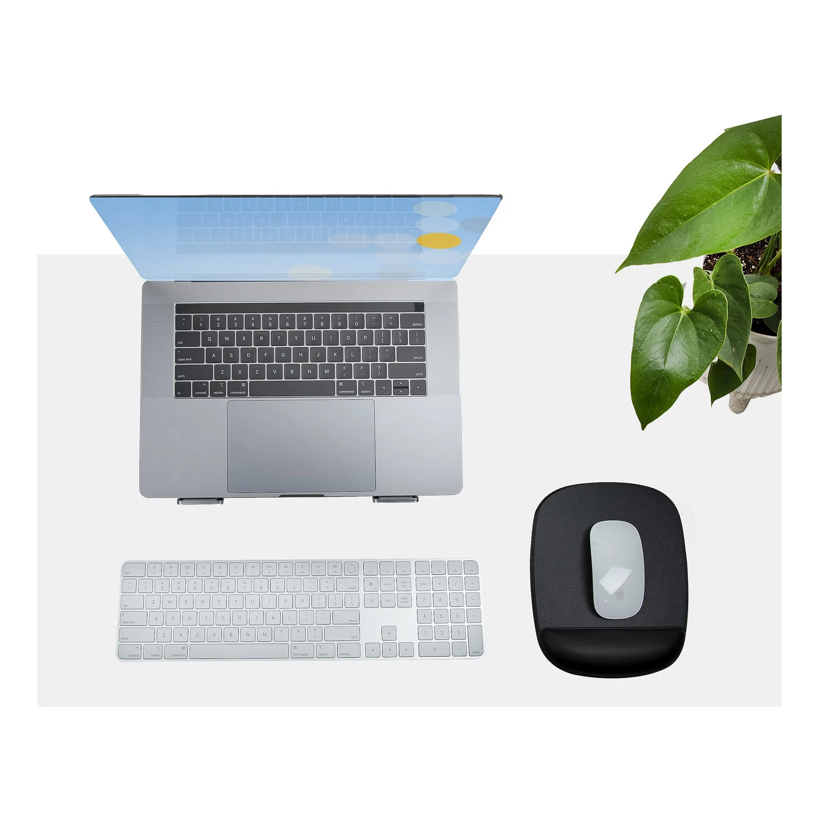 Tapis de souris noir avec souris et repose-poignets, posé sur un bureau blanc à côté d'un laptop et d'un clavier, vue du dessus
