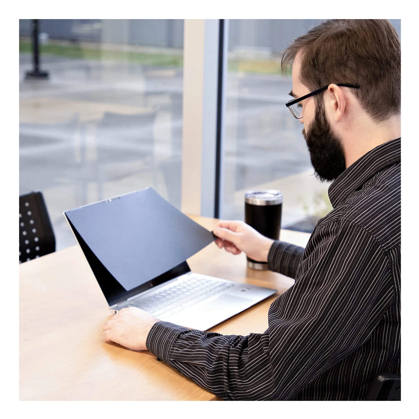 Utilisateur en open space basculant le filtre vers l'arrière du laptop pour partager son écran