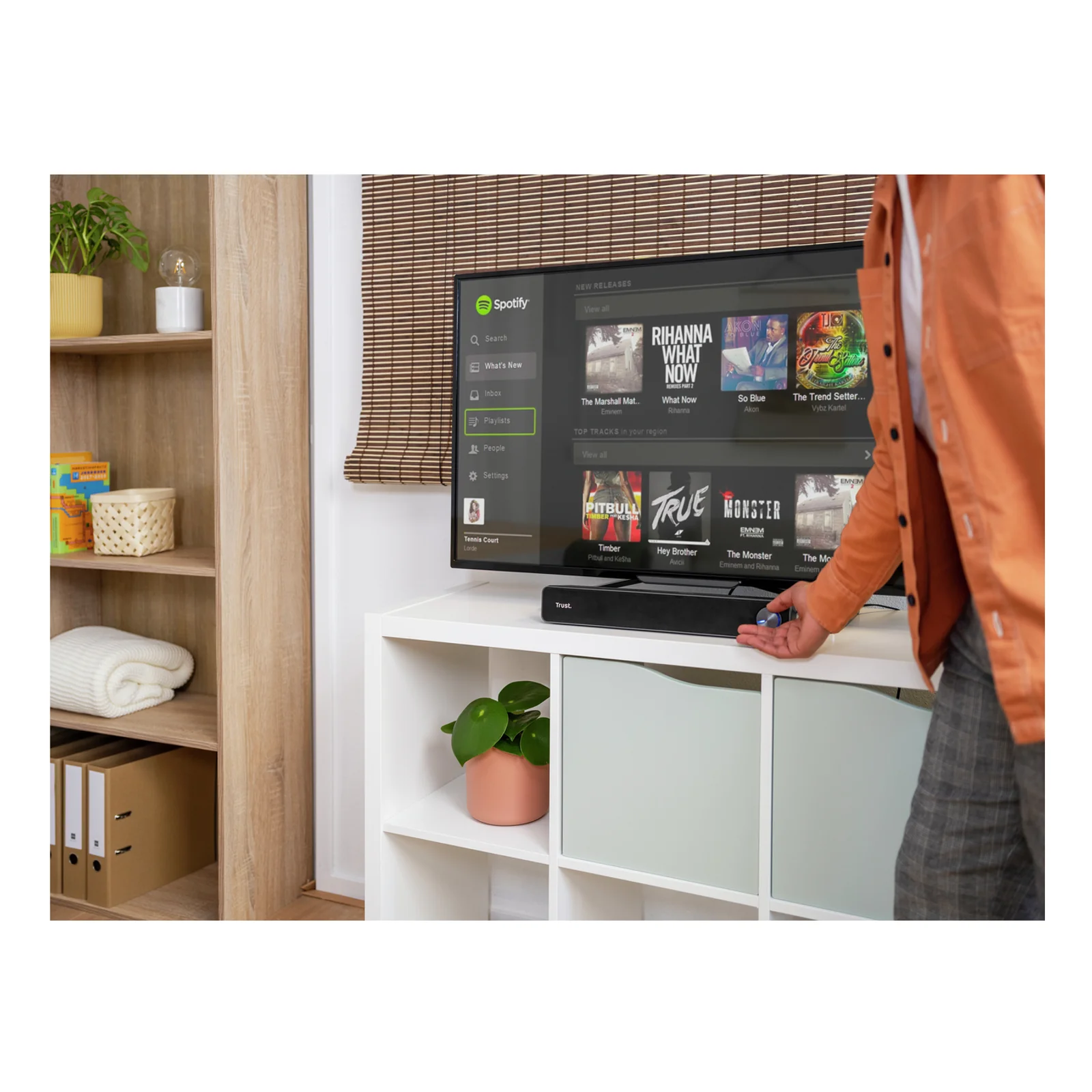 Personne tenant une télécommande face à un téléviseur sur meuble, usage en appoint TV