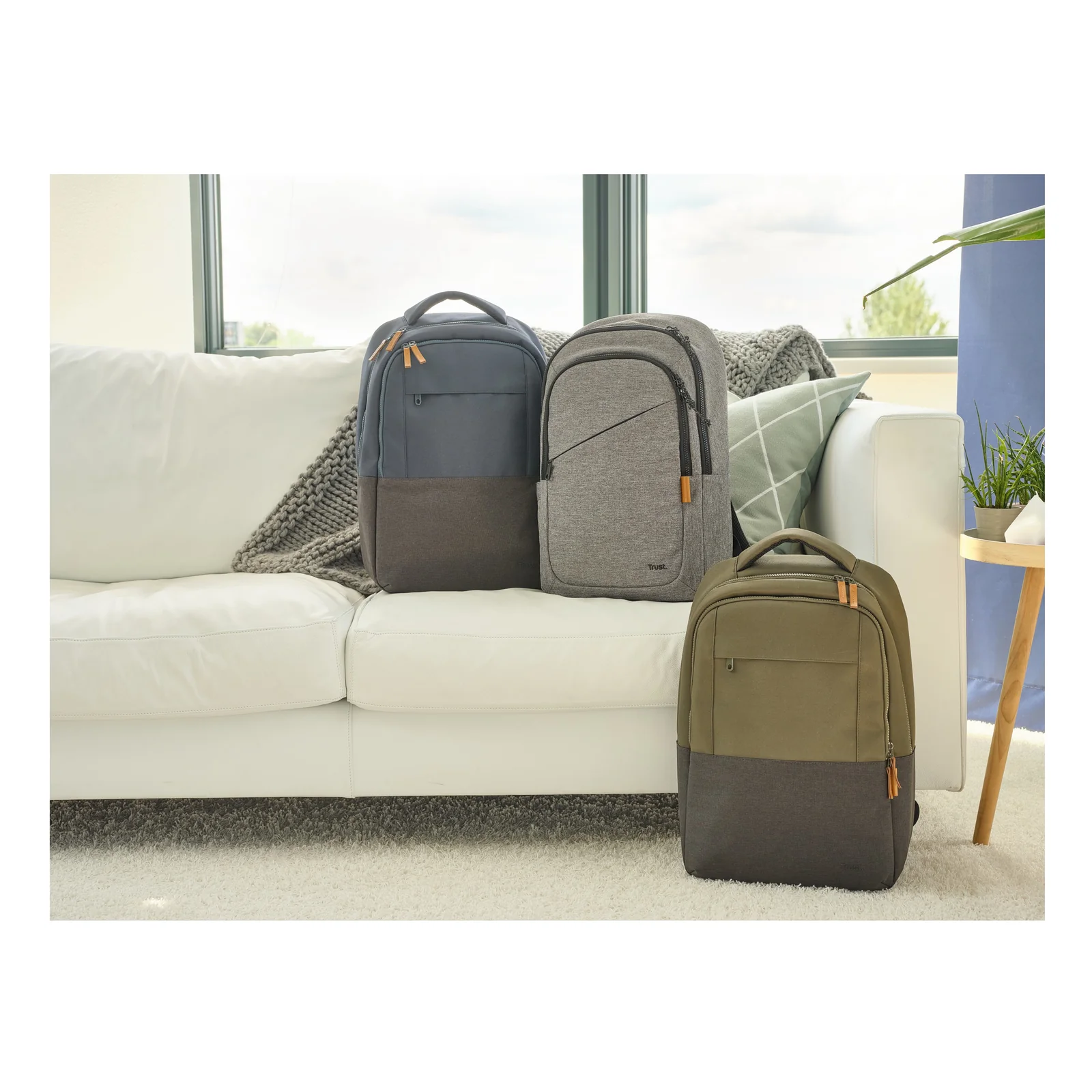 Trois sacs à dos Trust Avana côte à côte sur un canapé, coloris gris foncé, gris clair et kaki