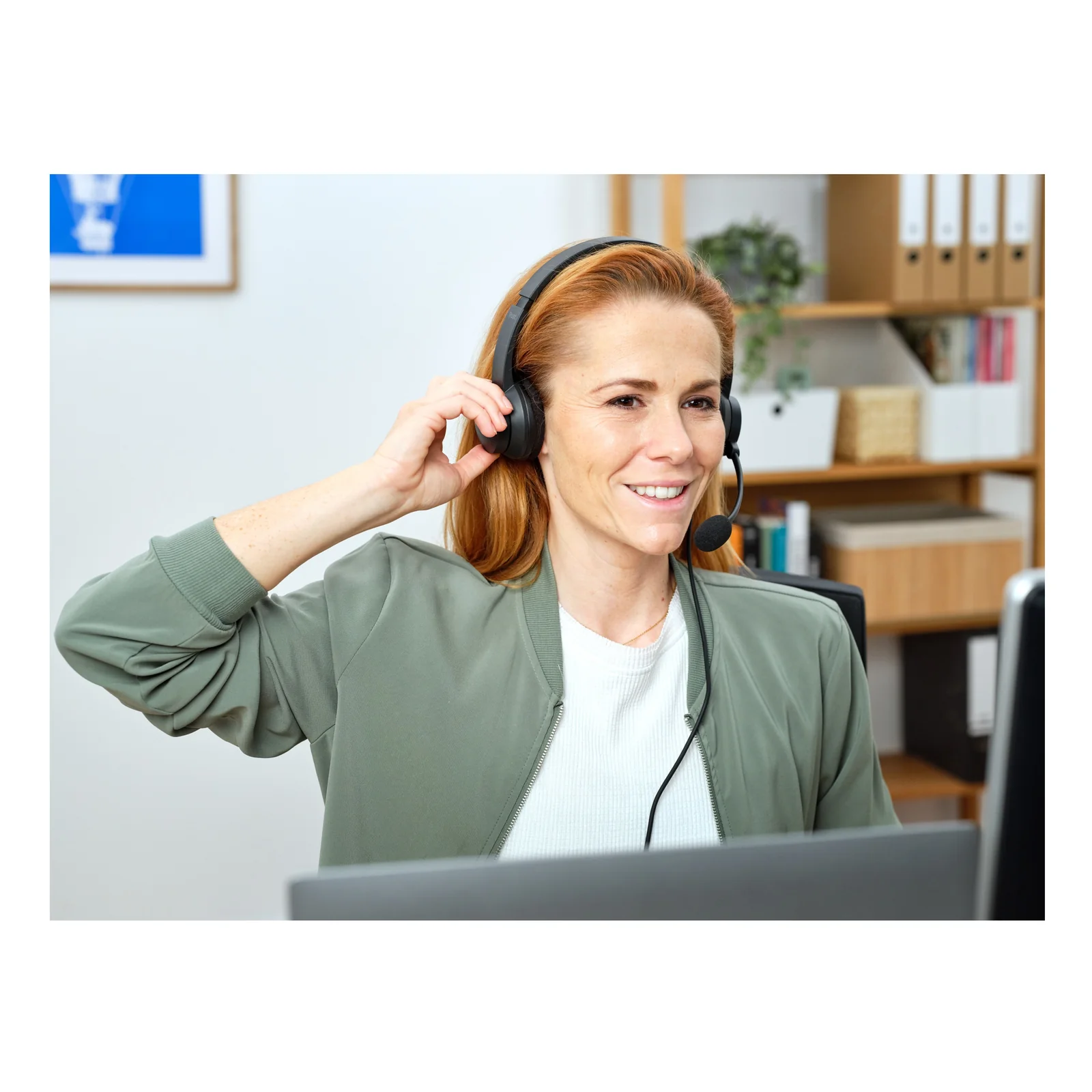 Femme portant un casque binaural filaire noir dans un open space lumineux