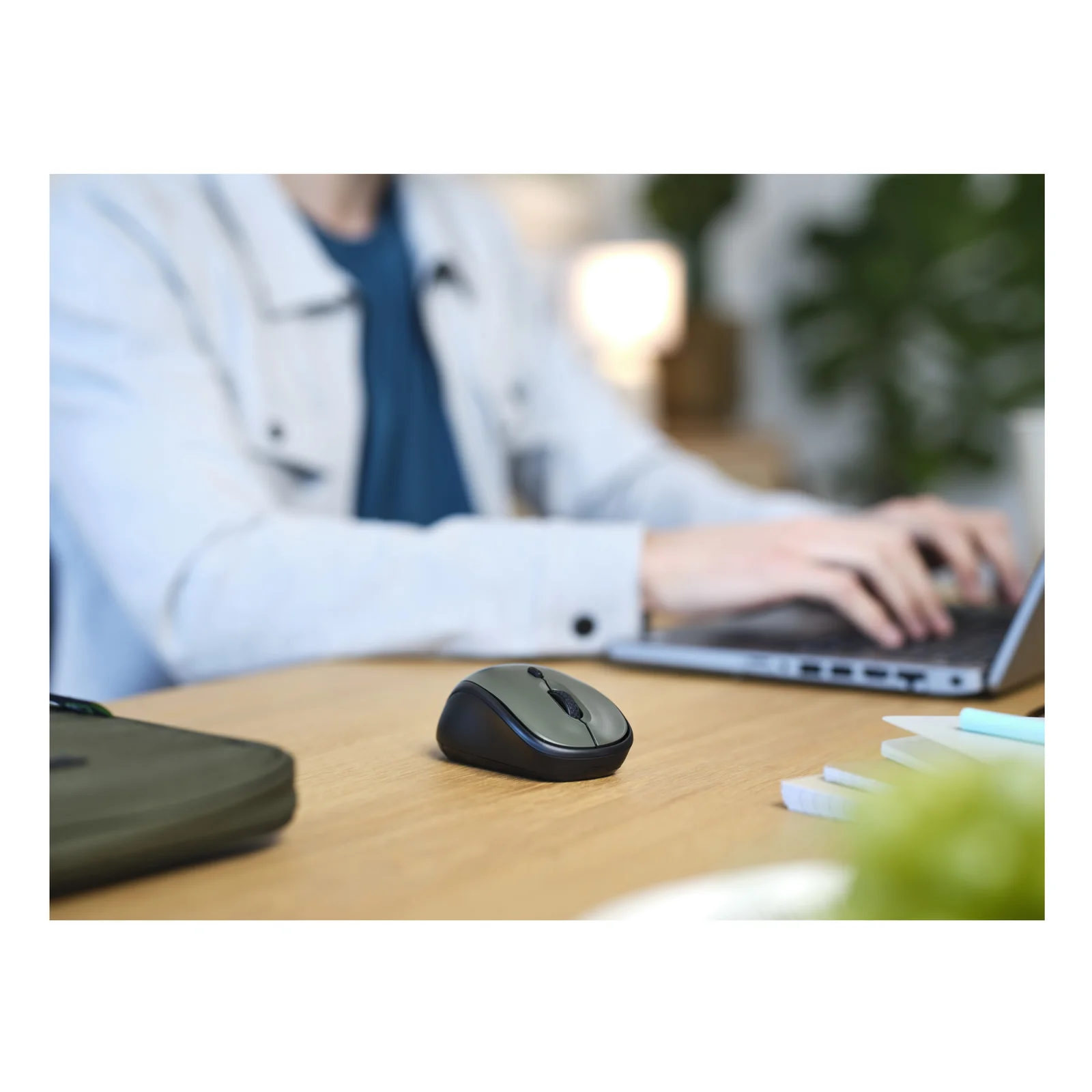 Photo lifestyle, personne utilisant un ordinateur portable sur bureau en bois, sac et souris Trust verts