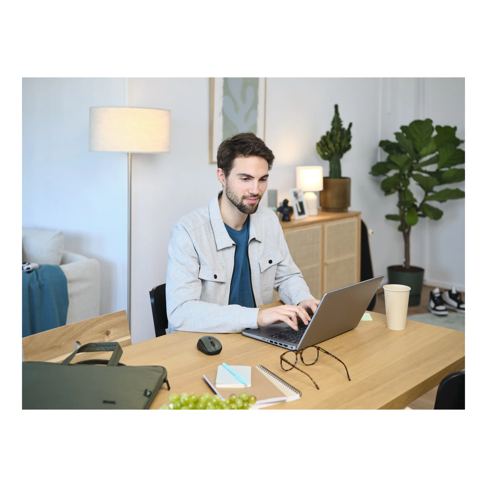 Photo lifestyle, homme au bureau à domicile avec laptop, sac Trust vert et souris visibles