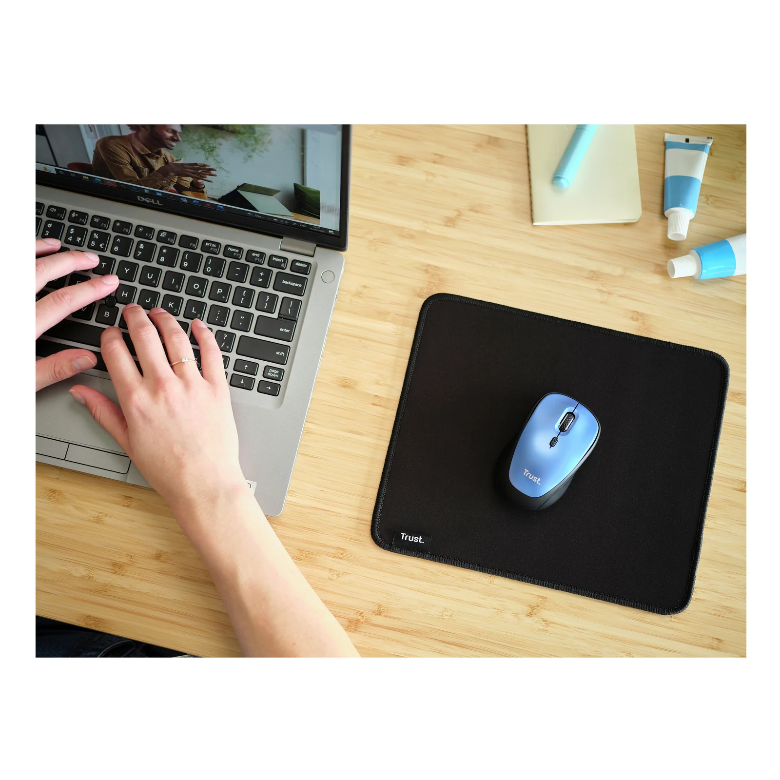Mains sur clavier d'ordinateur portable, souris bleue sur Trust Boye Noir, bureau en bois