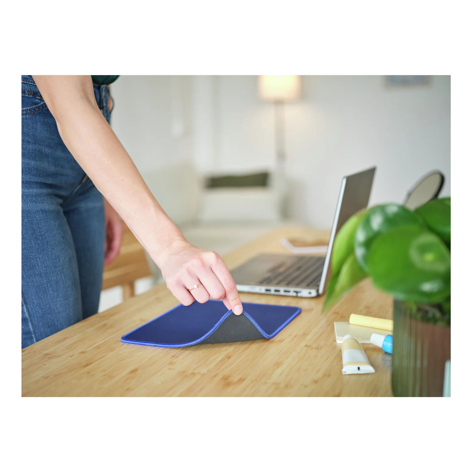 Main essuyant la surface du tapis Trust Boye bleu sur un bureau en bois