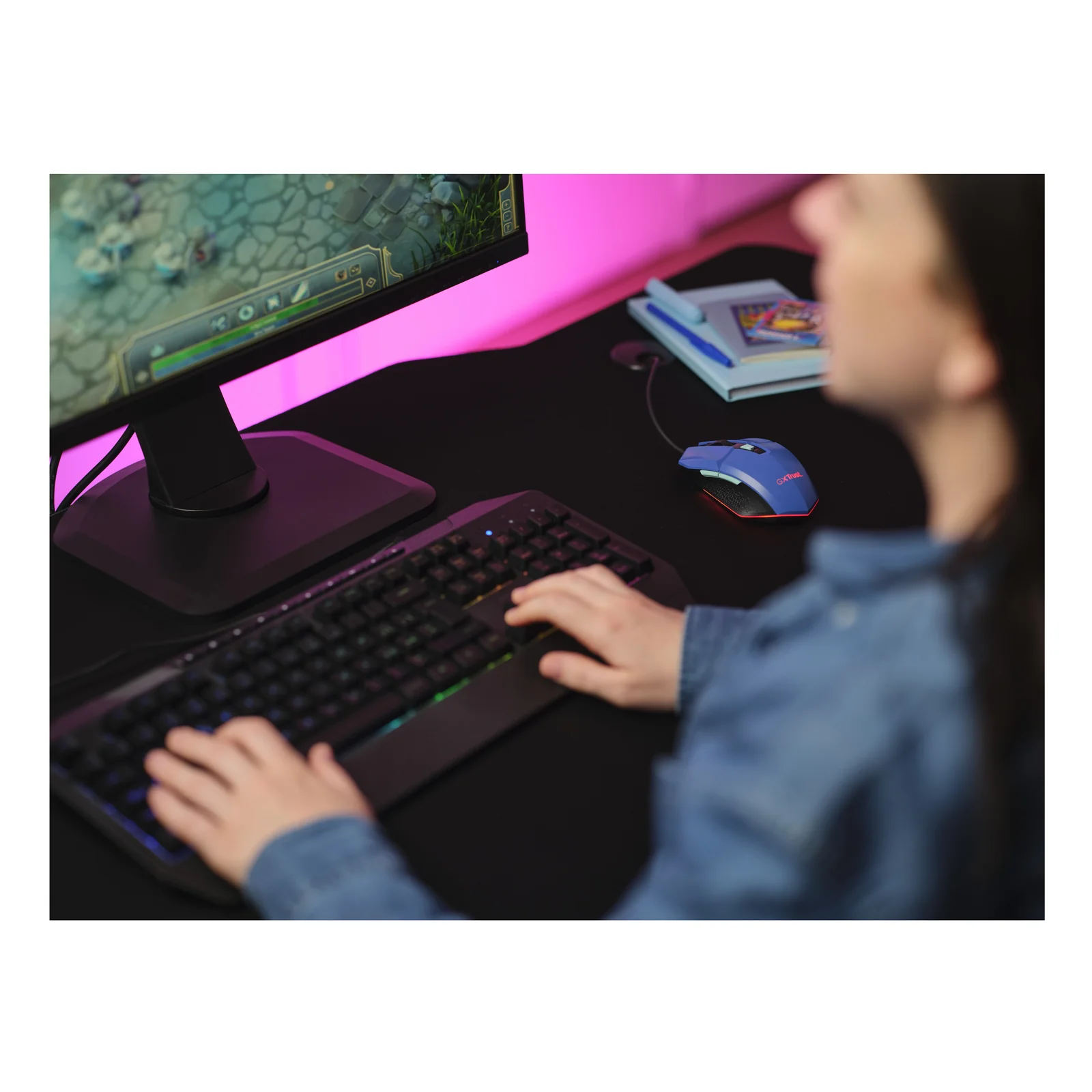 Utilisatrice jouant sur PC avec la souris Trust Felox bleue, ambiance lumières roses