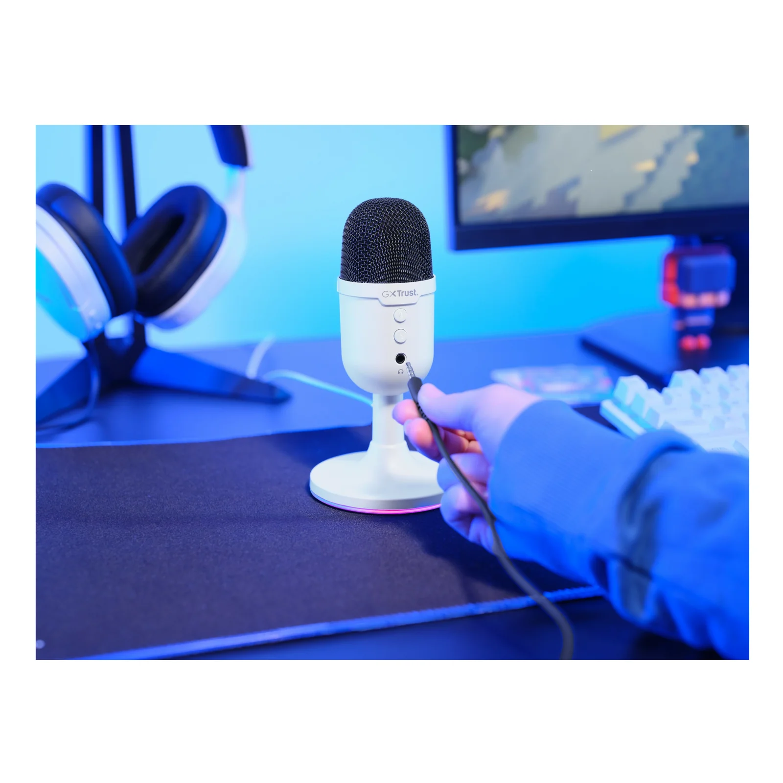 Micro Yunix blanc utilisé sur bureau gaming, main posée à côté, setup en arrière-plan
