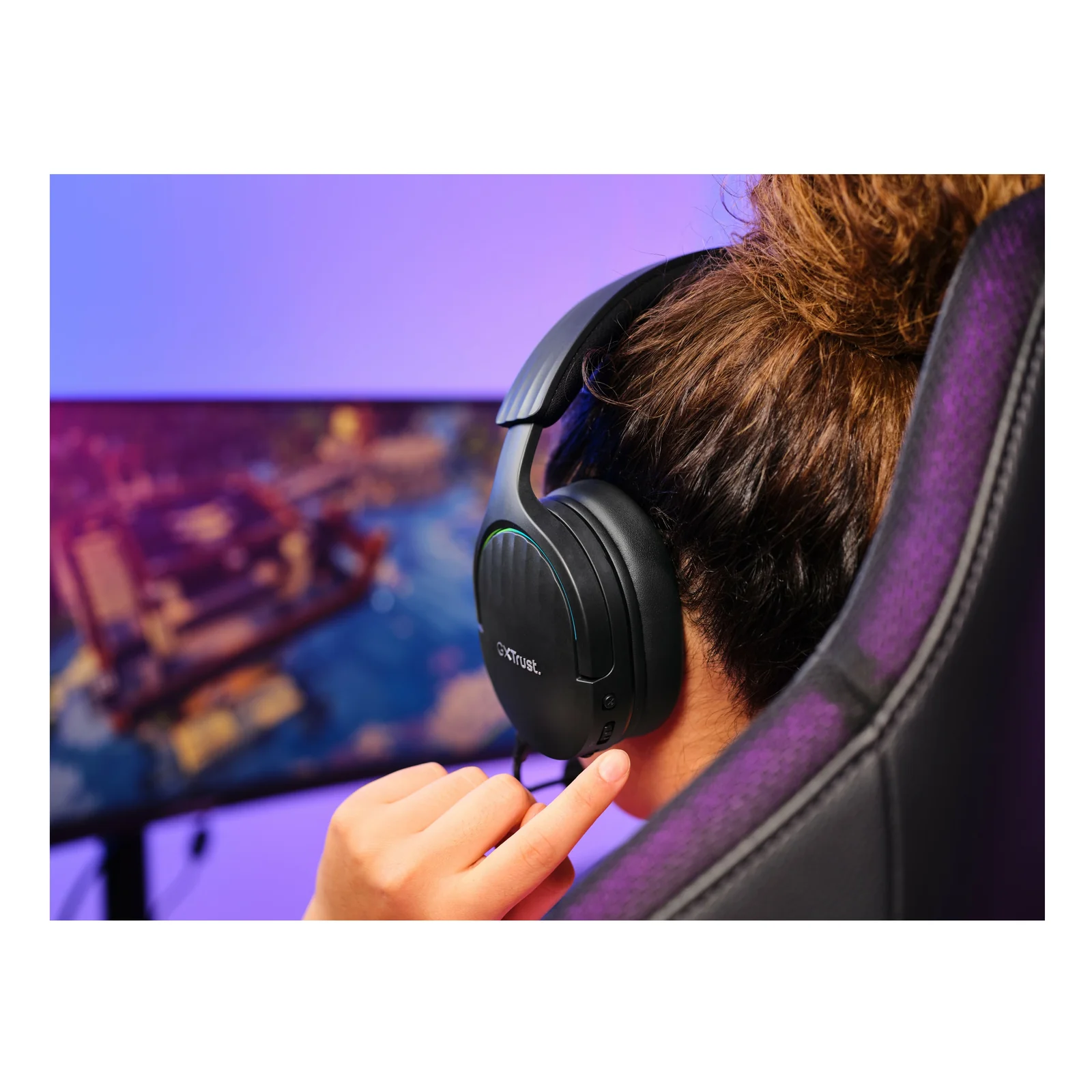 Joueuse portant le Trust GXT 491 Fayzo, configuration gaming en arrière-plan, éclairage violet