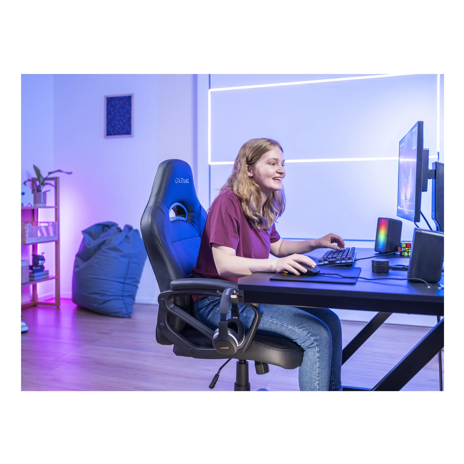 Utilisateur assis à un bureau gaming avec enceintes Trust GXT 611 Wezz au premier plan, ambiance bleue