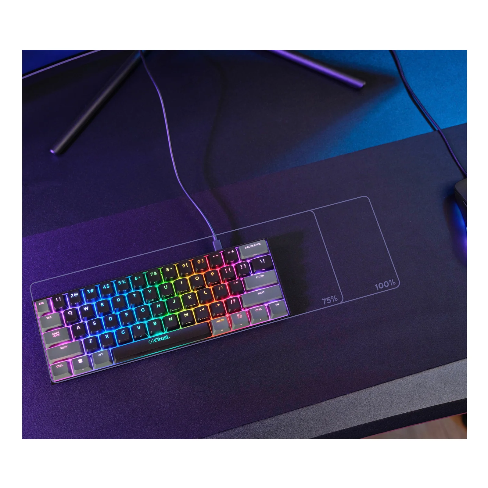 Clavier Trust GXT 867 Acira posé sur bureau sombre, rétroéclairage RGB multicolore allumé en ambiance gaming