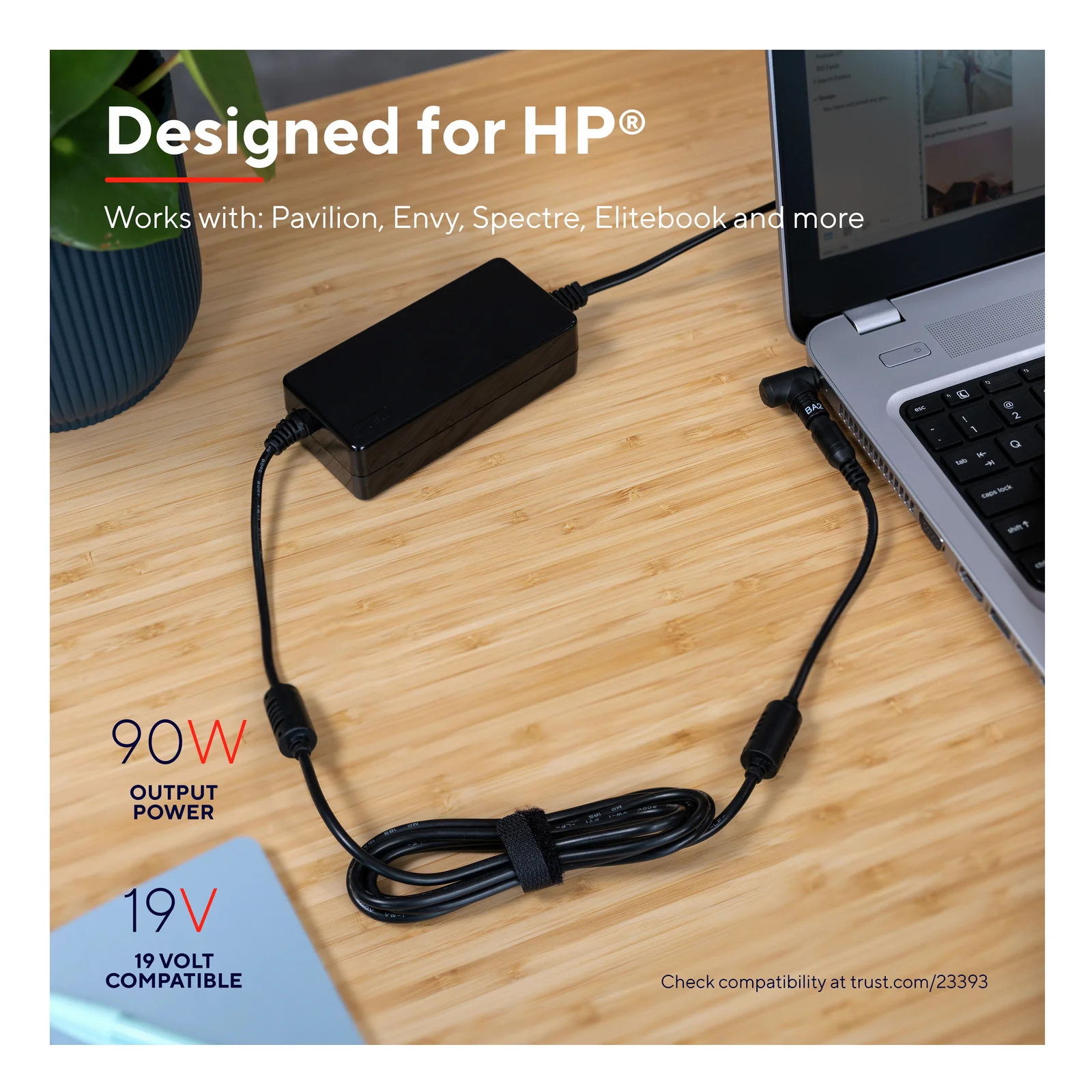 Trust Maxo 23393 branché à un PC portable HP sur bureau en bois, câble visible, mention 90 W et 19 V