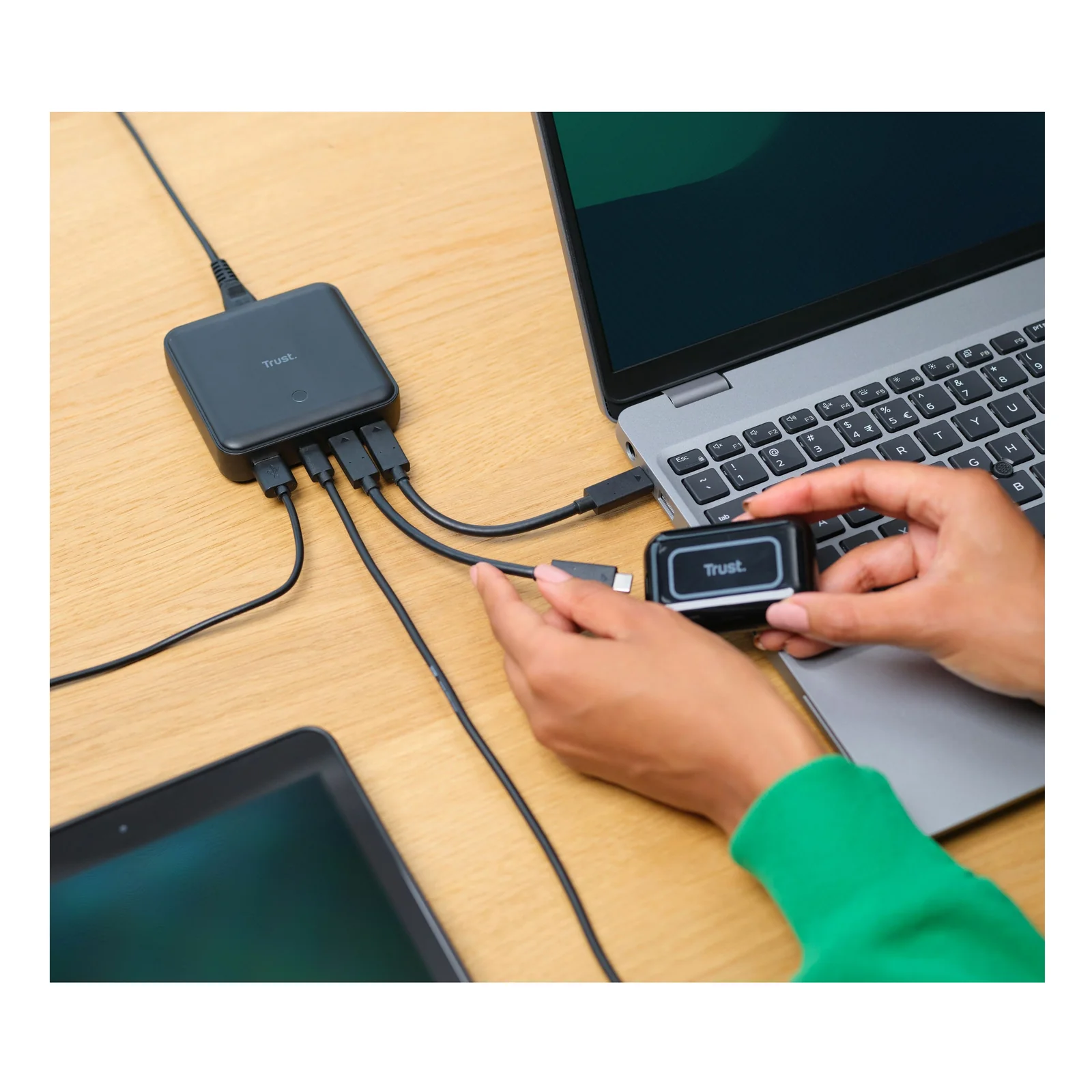 Main connectant un appareil au Trust Maxo sur un bureau, ordinateur portable visible en fond