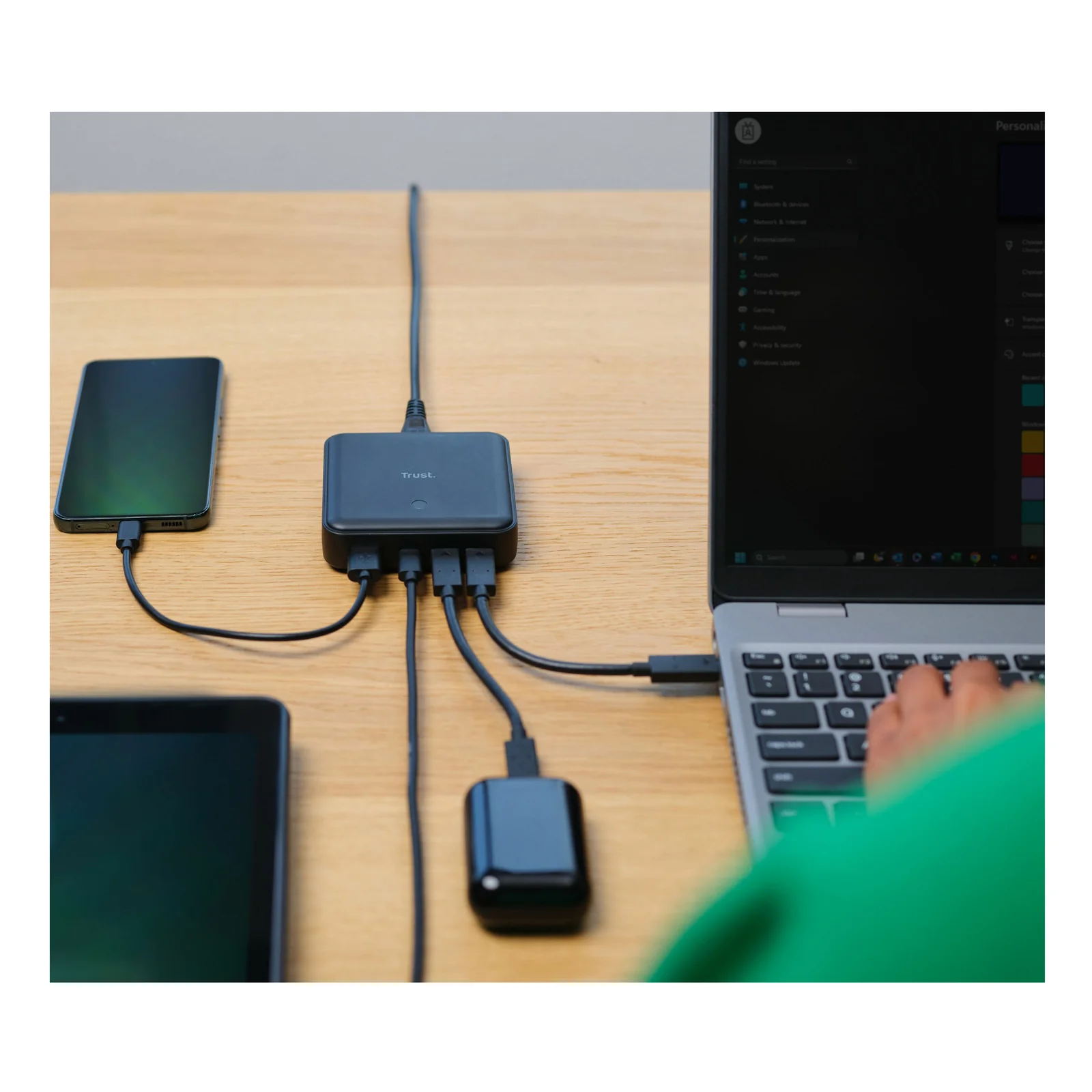 Chargeur Trust Maxo avec plusieurs câbles connectés posé sur un bureau, ordinateur portable