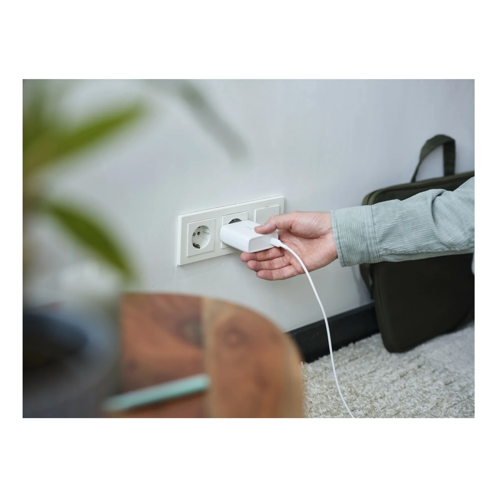 Photo d'ambiance, main branchant le chargeur blanc Trust Maxo dans une prise murale