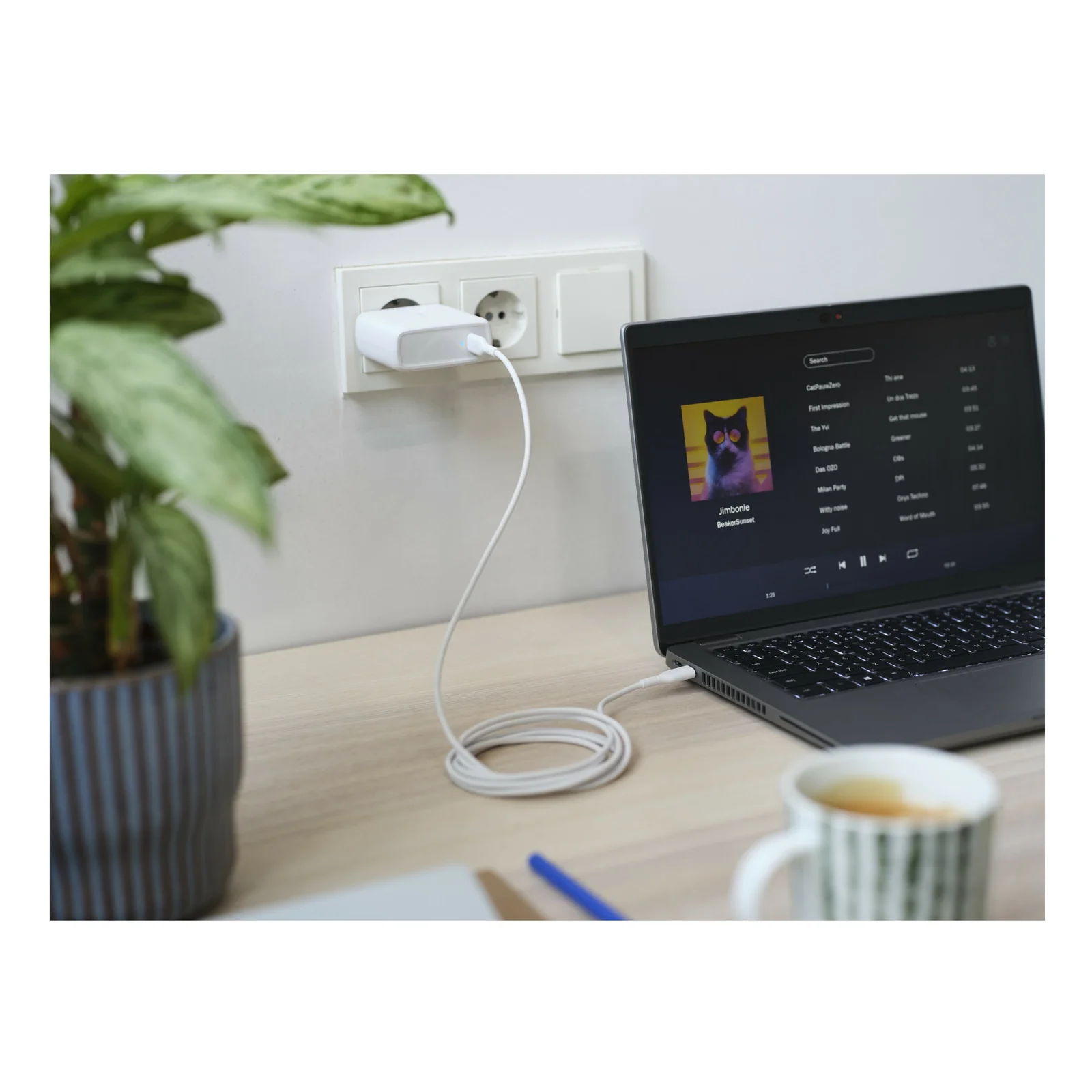 Photo d'ambiance, chargeur Trust Maxo branché au mur, câble USB-C relié à un ordinateur portable sur bureau