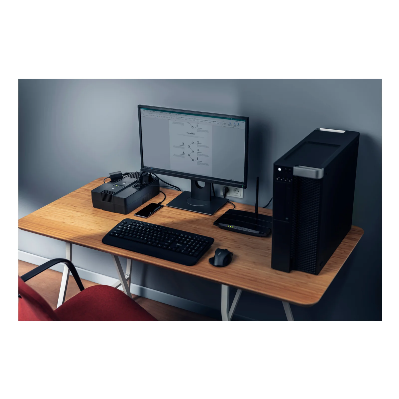 Trust Maxxon 800 VA posé sur un bureau avec tour PC, écran et clavier