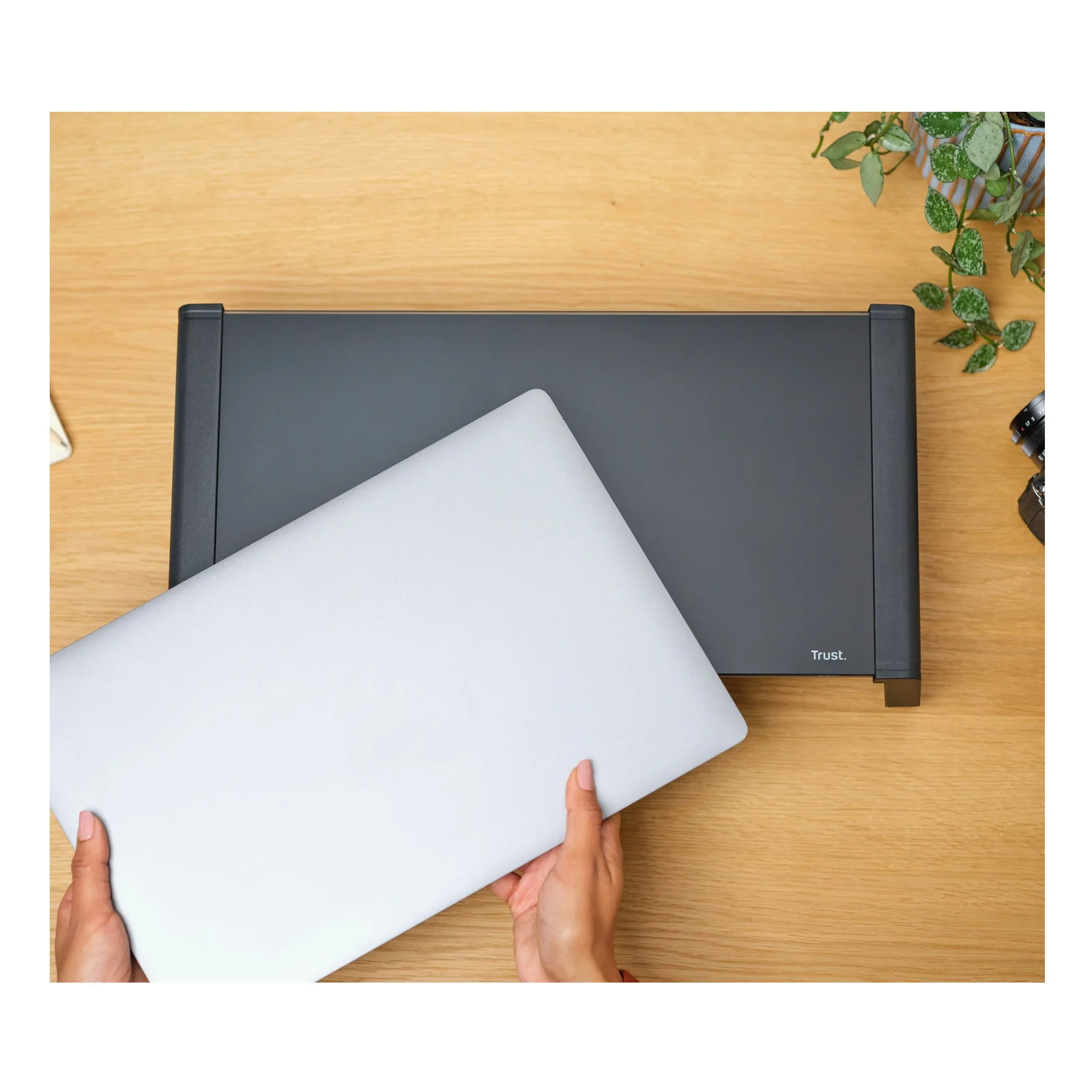 Mains glissant un laptop blanc sous le plateau en verre du support bureau