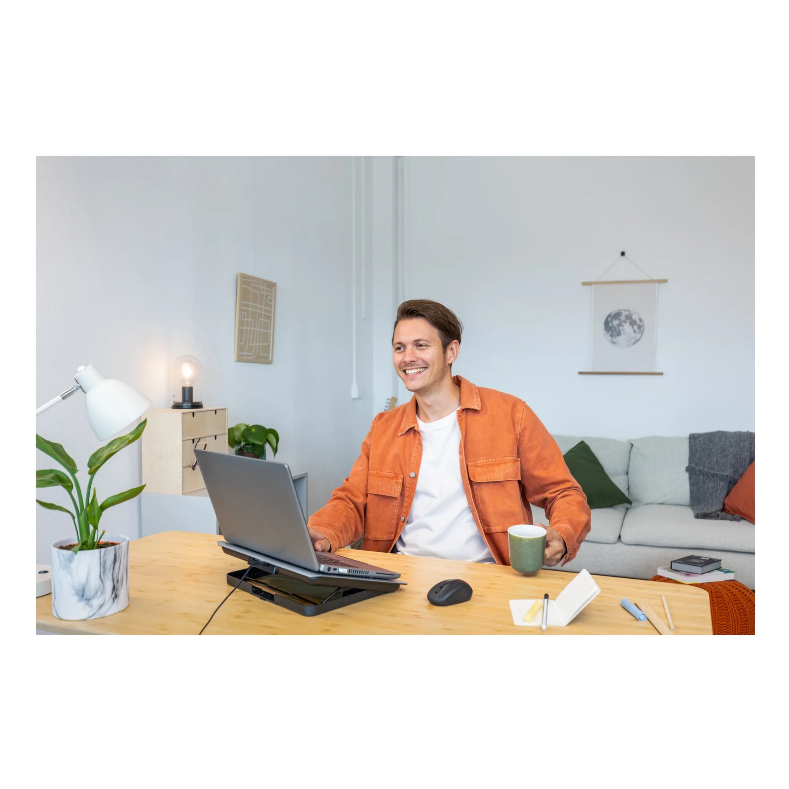Homme souriant assis à un bureau avec ordinateur portable et souris sans fil