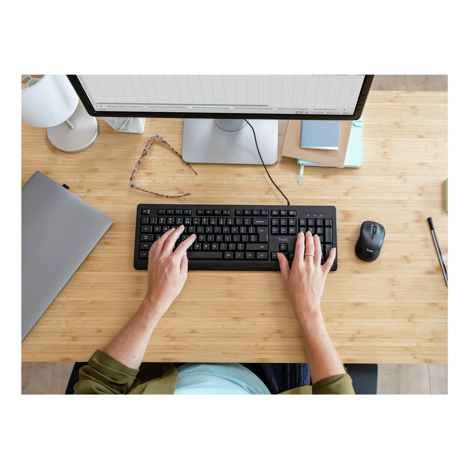 Vue du dessus, deux mains sur clavier et souris Trust TM-201 posés sur bureau en bois