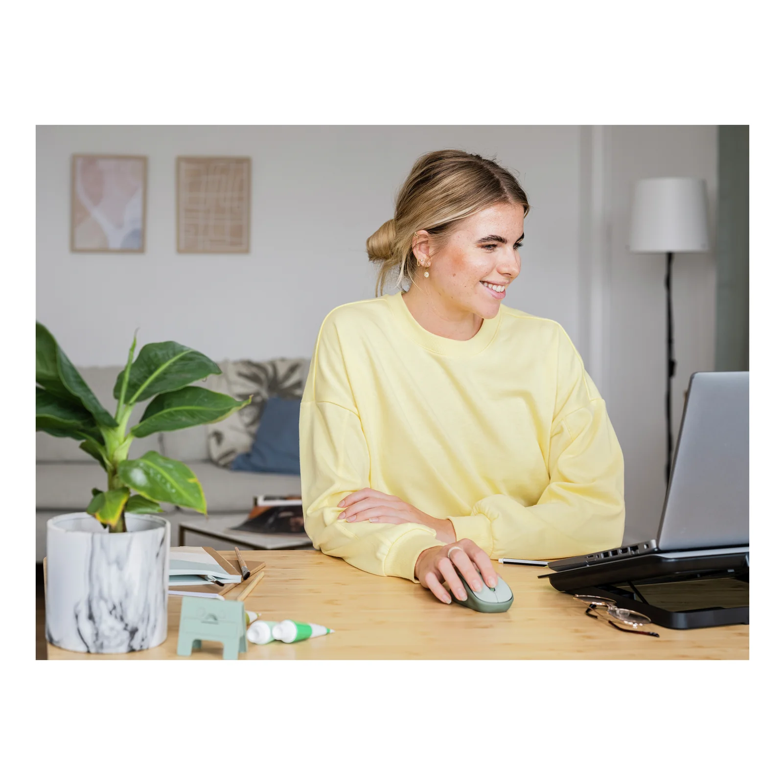 Plan rapproché d'une femme utilisant la souris Trust Yvi+ verte sur bureau, ordinateur portable au fond