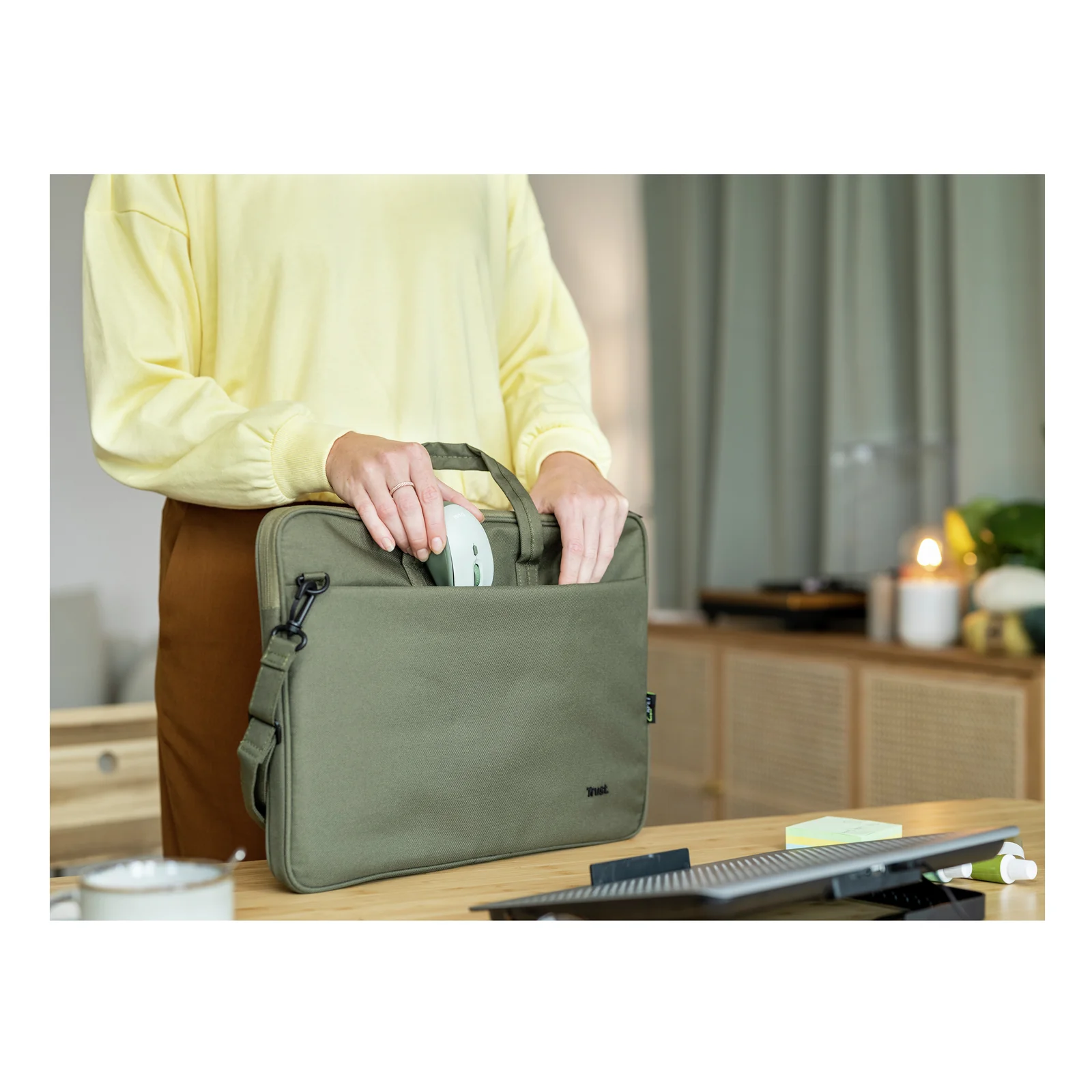 Main glissant la souris Trust Yvi+ verte dans un sac à bandoulière vert olive